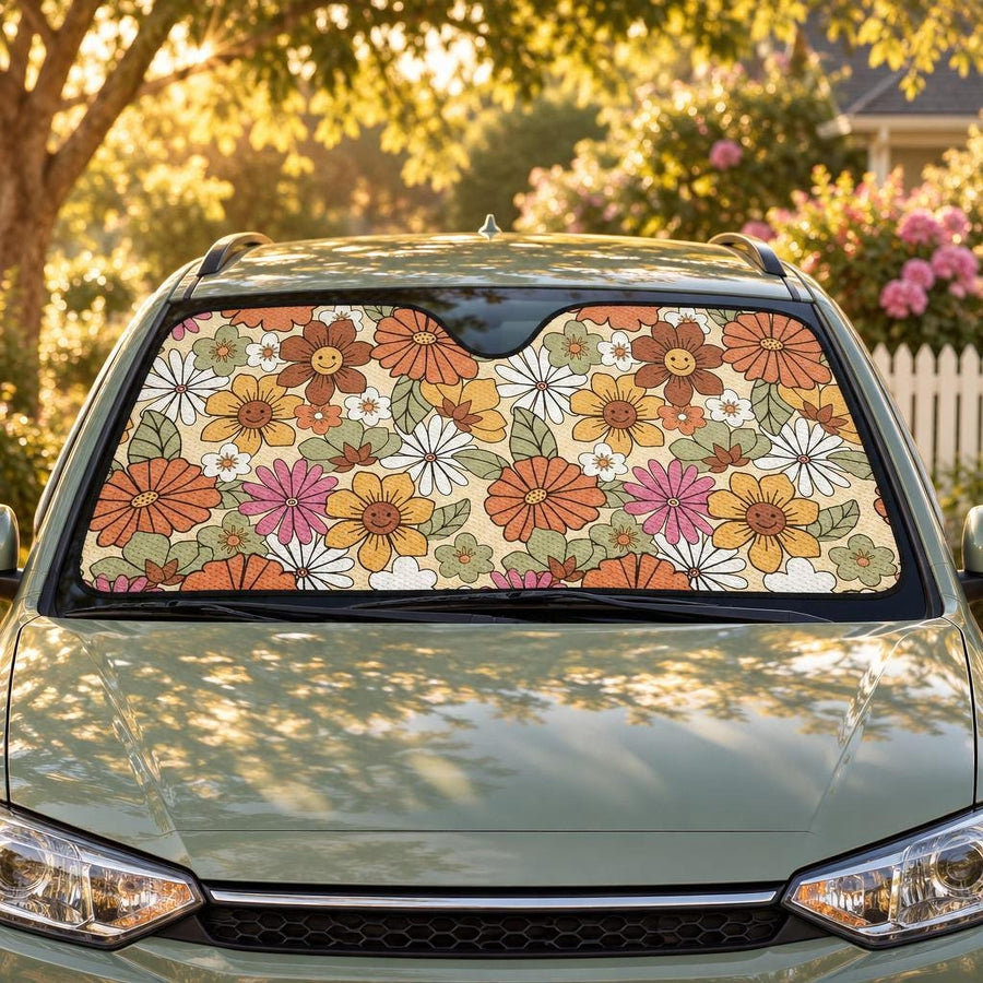 Flower Power Car Shade fitted in the windscreen of a sage-green hatchback on a leafy street at golden hour, printed side facing out
