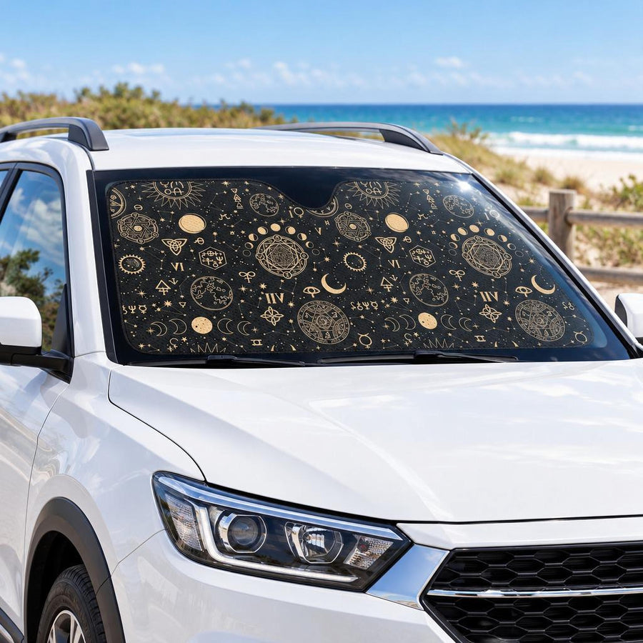 Black And Sand Celestial Car Shade fitted in the windscreen of a white SUV parked at a sunny beach, printed side facing out