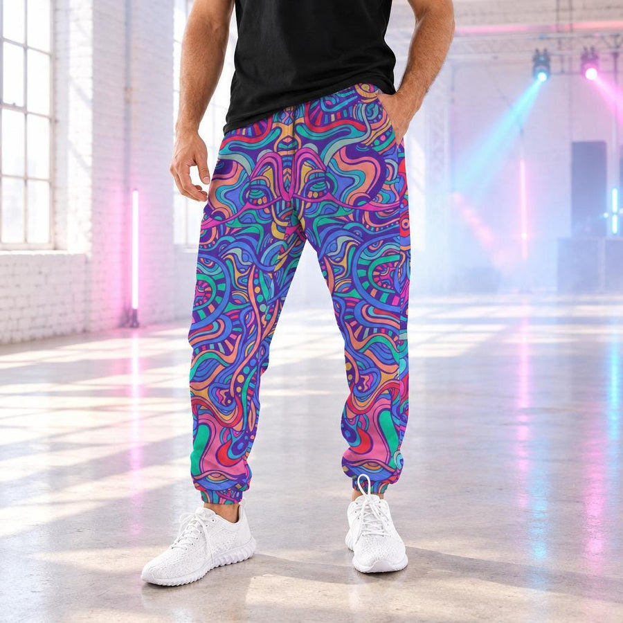 Psychedelic Aurora Men's Track Pants worn with white sneakers in a bright daytime warehouse rave space with pastel stage lights