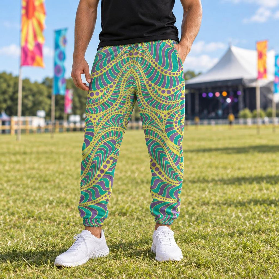 Yellow Spirit Men's Track Pants worn with white sneakers at a sunny outdoor music festival with colourful flags