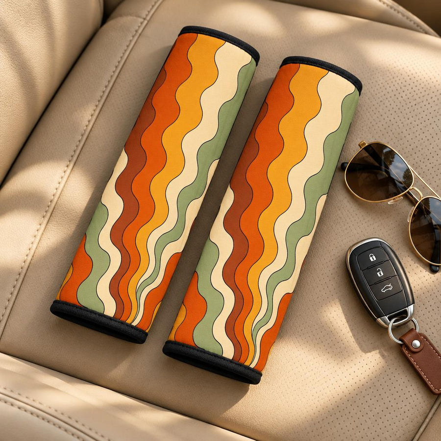 Retro Groovy Vibes Seat Belt Covers (Set of 2) lying side by side on a tan leather car seat with sunglasses and a car key