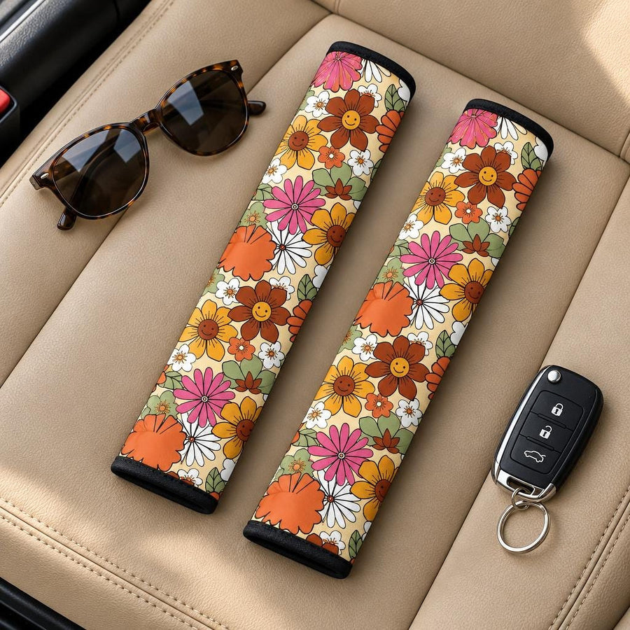 Flower Power Seat Belt Covers (Set of 2) lying side by side on a tan leather car seat with sunglasses and a car key