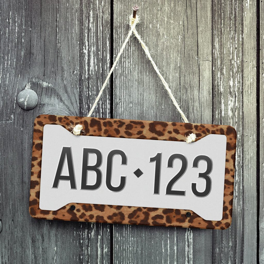 Leopard License Plate Frame displayed on a wooden wall